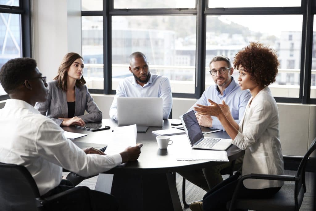 Millennial businesswoman addressing colleagues at a corporate business meeting, close up