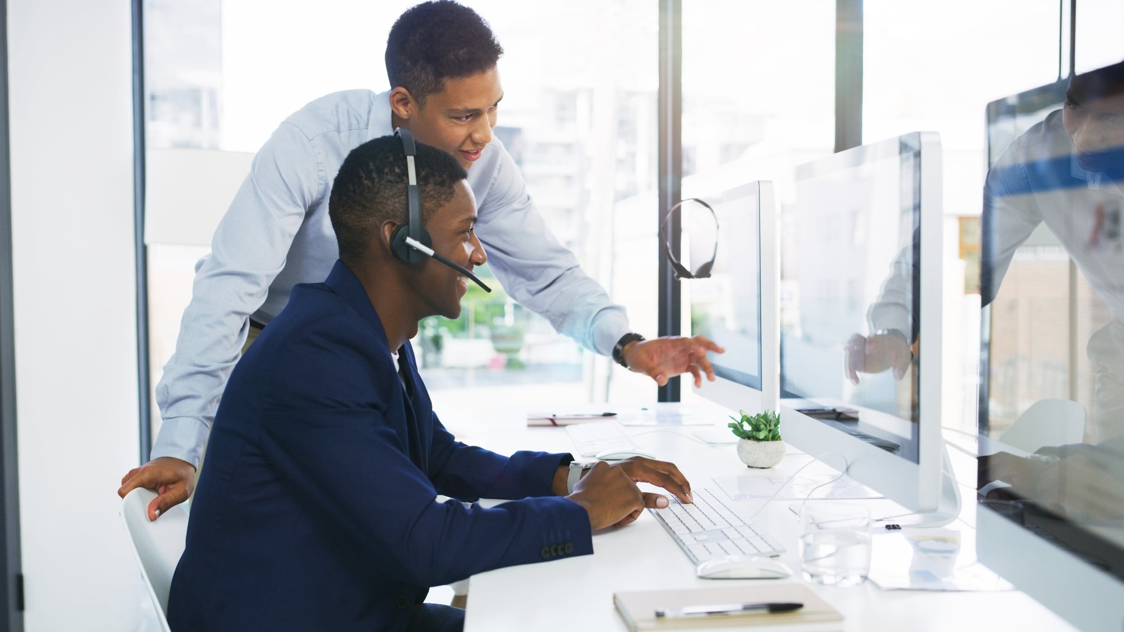 Shot of a young businessman assisting a colleague in a call centre