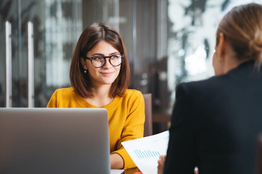Group of happy business people have meeting at workplace in office. Two positive woman working together using modern laptop for working concept Group of happy business people have meeting at workplace in office. Two positive woman working together using modern laptop for working concept