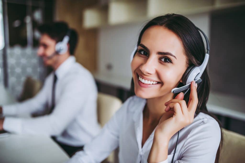 How can I help you? Beautiful call center workers in headphones are working at modern office.